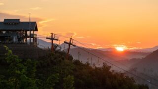 The sky painted in hues of orange and pink as the sun sets over the Gatlinburg SkyPark, with the silhouette of the mountains in the distance.